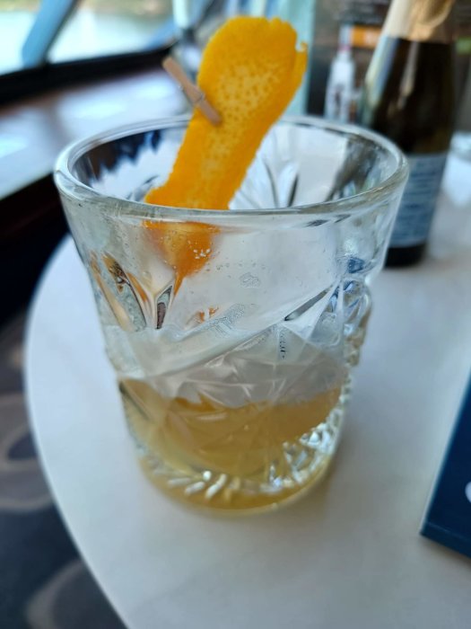 Ett glas Zacapa sour cocktail med is och en apelsinskal-garnityr.