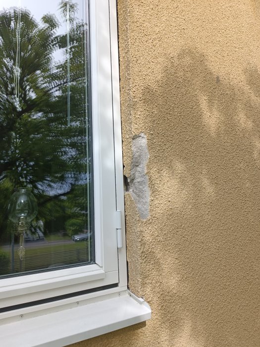 Skador på stänkputsade fasaden nära nyinstallerat fönster på hus från -49.