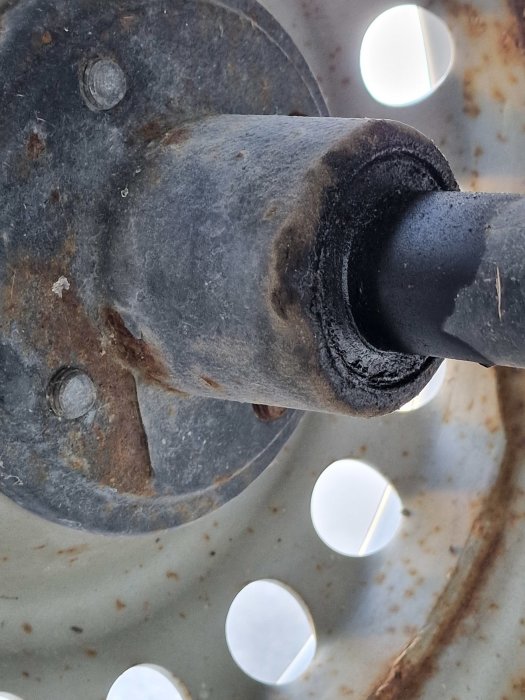 Närbild på ett fordons hjullager och axel som visar tecken på slitage och rost.