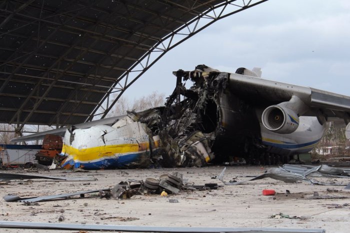 Kraschad och sönderdelad fraktflygplan i en hangar med skräp och vrakdelar runtomkring.