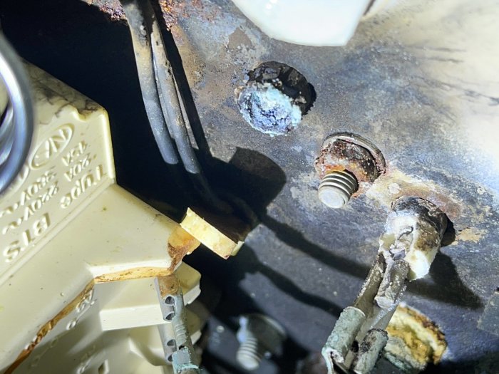 Korroderade kabelkontakter och rostig anslutning på en vattenberedares öppna lucka.