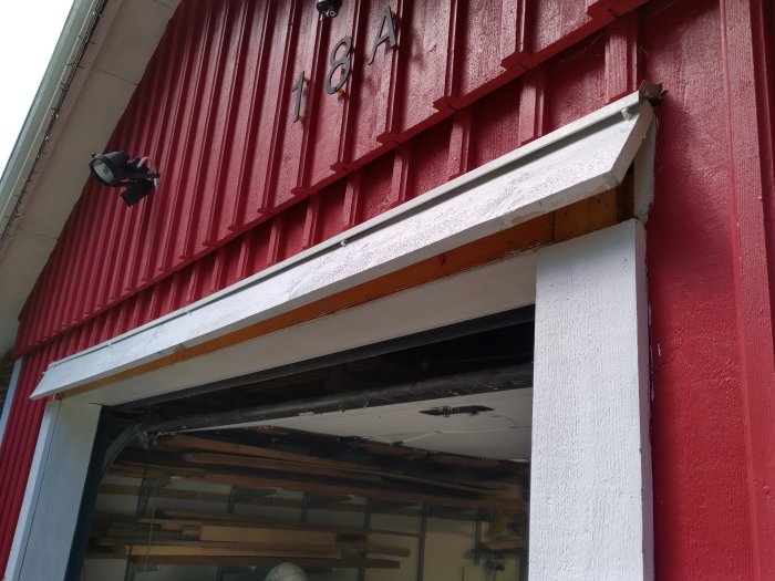 Röd garagets fasad med en vit borttagen bräda för att passa in objektet.