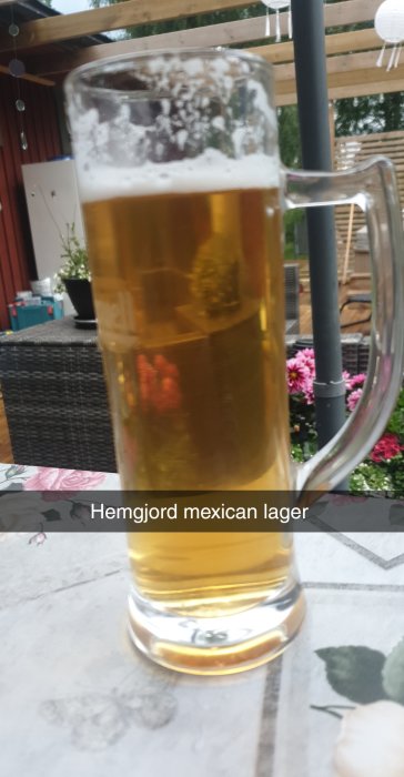 Ett glas med hemgjord mexikansk lageröl på ett utomhusbord.