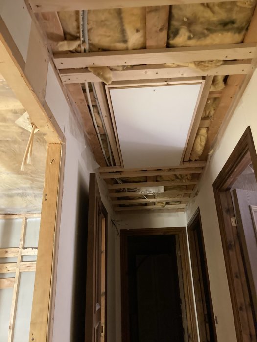 Renoverat takbjälklag i badrum med isolering, plywood och fortfarande oskyddad huntonitplatta.