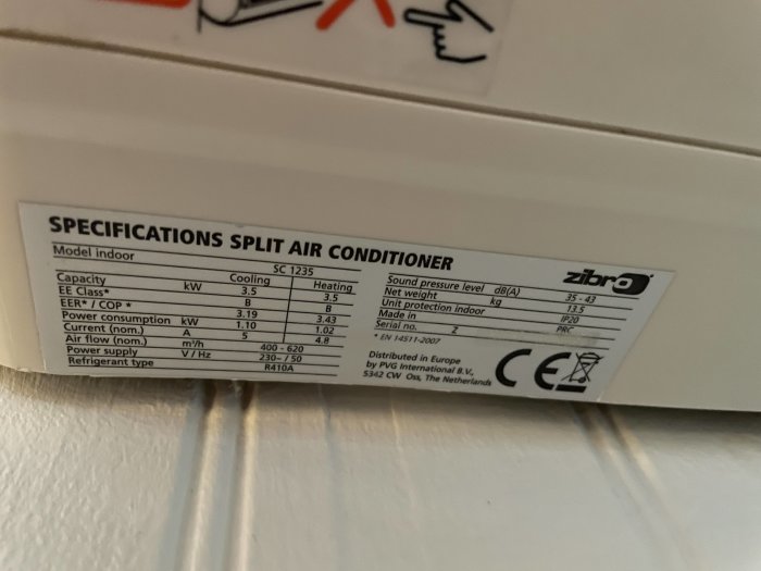 Etikett under en luftvärmepumps inomhusdel med specifikationer och modellinformation.