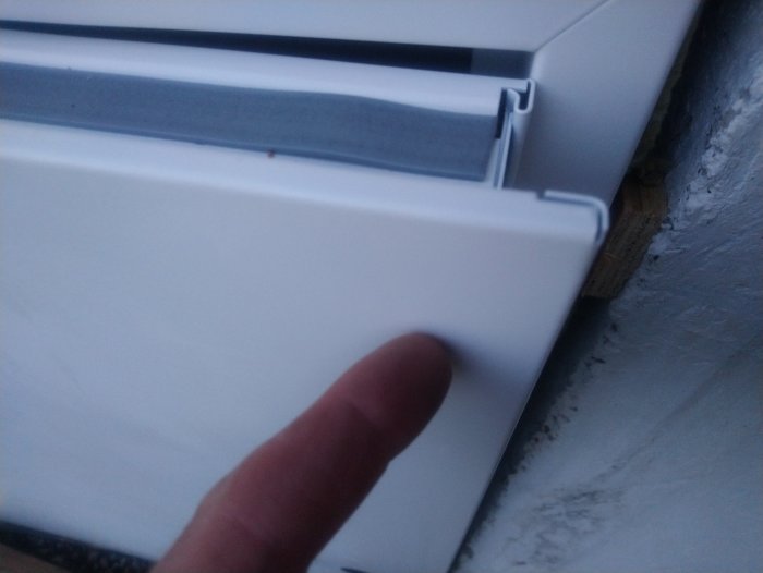 Finger som pekar på glipan mellan en dörrkarm och väggen där det är problem med monteringen.