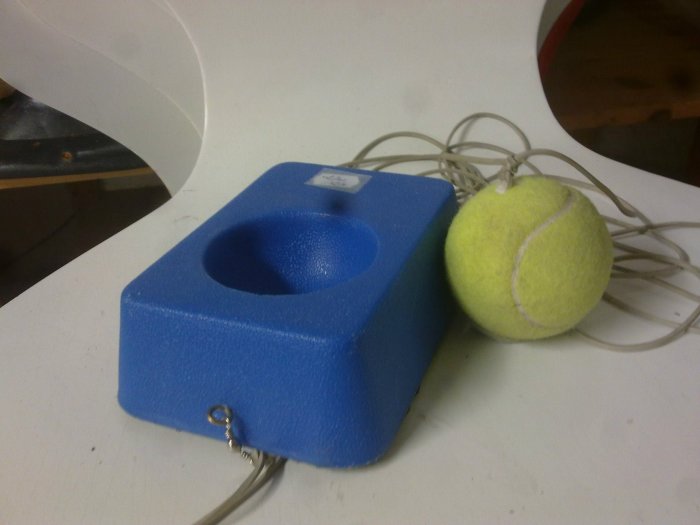 Blått kubformigt föremål med hål och en tennisboll med sladd, 80-tals retro teknikgadgets.