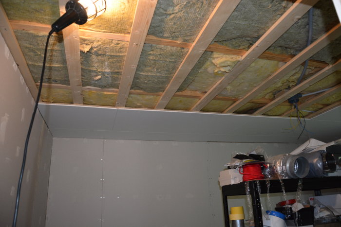 Innertak med isolering och gipsskivor under arbete i ett rum under renovering.
