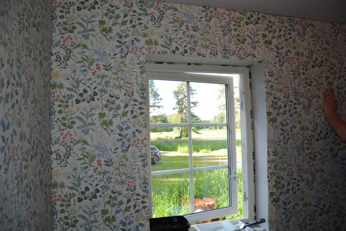 Blommig tapet från Boråstapeter i ett sovrum med öppet fönster som visar landskapet utanför.