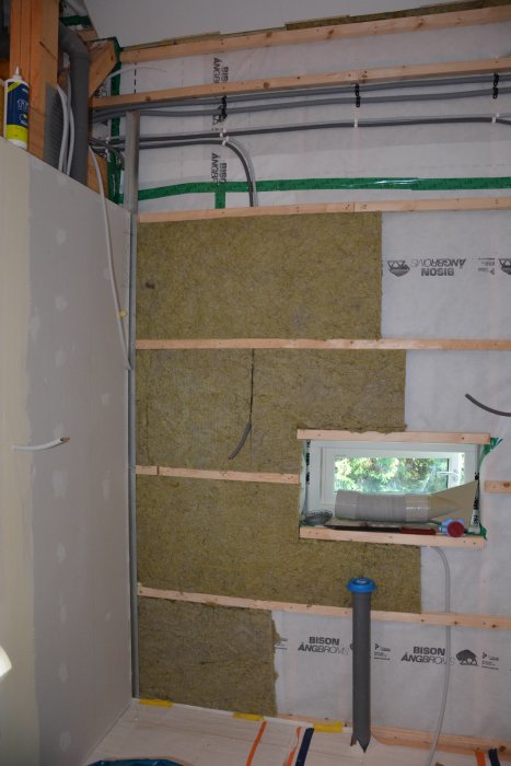 Renoveringsprocess med isolering och elinstallationer i ett oavslutat rum med synliga väggstommar.
