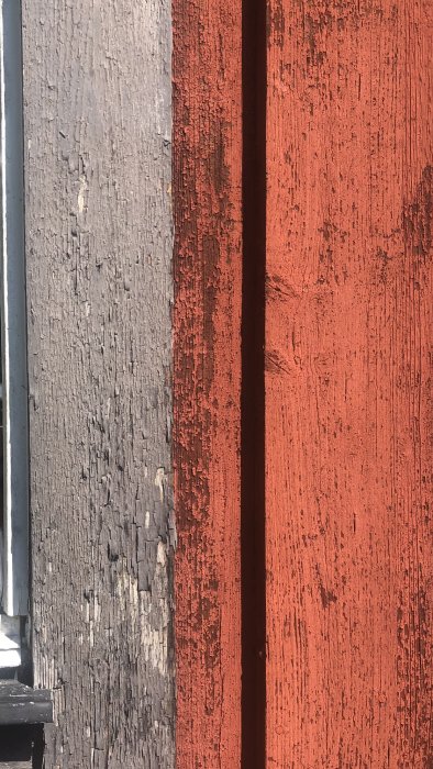 Närbild på slitet träfoder och vindskivor med flagande grå och röd färg.