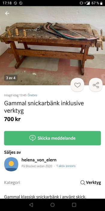 Gammal sliten snickarbänk med några verktyg, bl.a. en såg och träklossar, på en röd betonggolv.