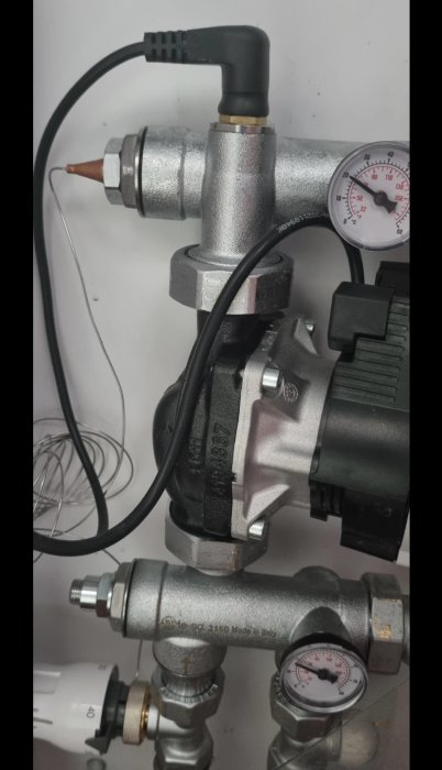 Shunt och pump för golvvärmen med termostat och manometrar i en teknisk anläggning.