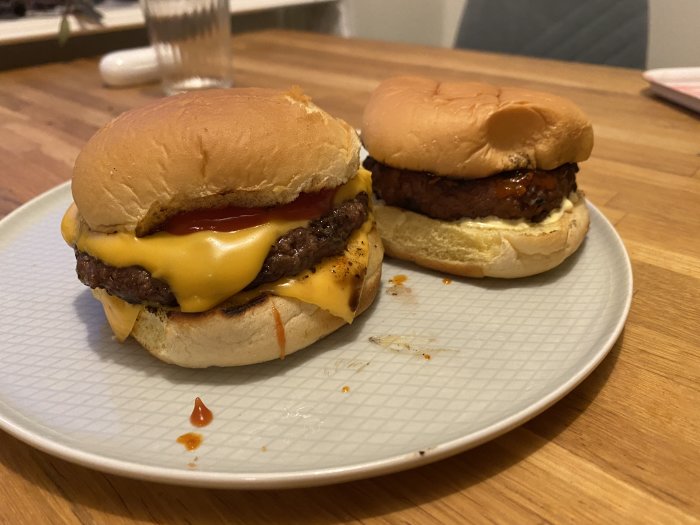 Två cheeseburgare med smält ost och ketchup på en tallrik.