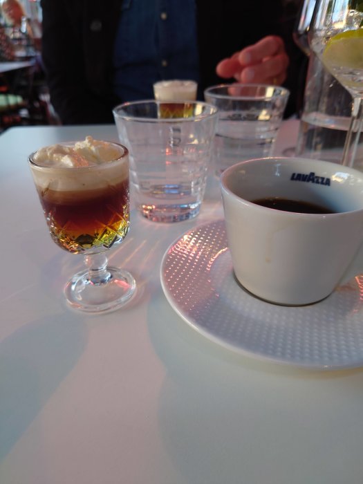 Drinkar på bord inklusive klassisk hotshot, okänd apple sour drink och espresso i Lavazza-kopp.