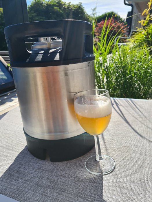 Ölfat och ett glas med tysk lageröl på en utomhusterrass i solljus.