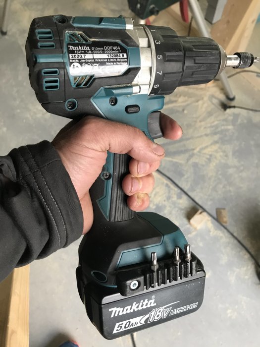 En hand håller en Makita skruvdragare med ett bits-magasin på batteriet.