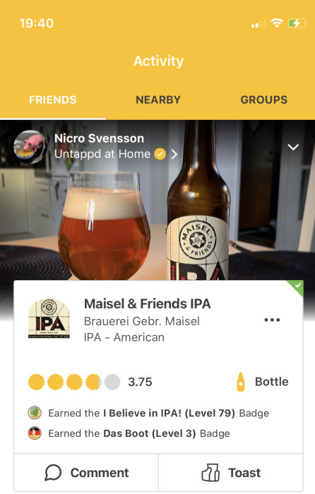 Ölglas med skumfylld IPA intill en ölflaska med etiketten "Maisel & Friends IPA" framför en appskärm med användarbetyg.