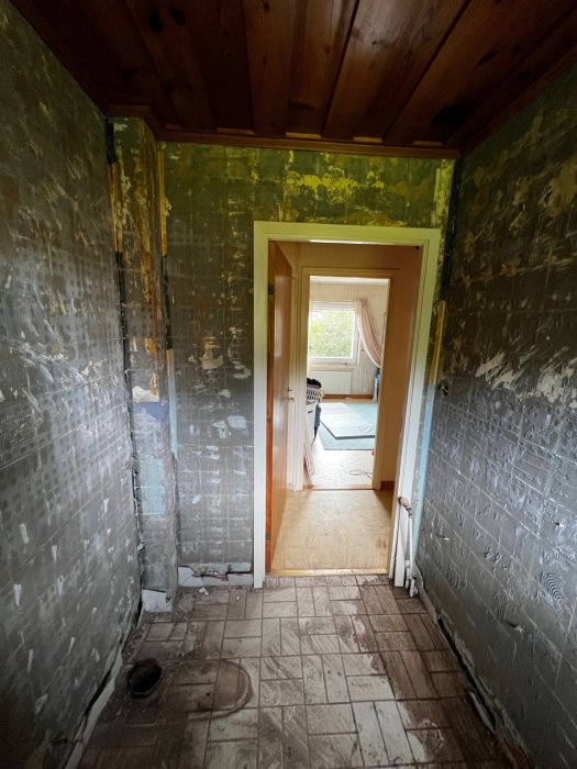 Tomt badrum efter rivning med nakna väggar och avlägsnade möbler, bjälklag i taket och tom golvyta.