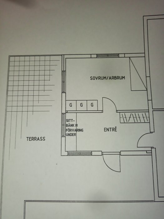 Ritning av husplan med markerad terrass, indikation på fall, entré och sovrum/arbrum.