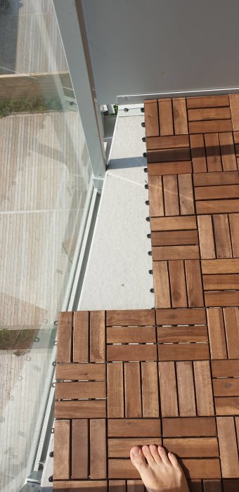 Utsikt över balkong med träplattor som behöver anpassas efter en sned balkongkant, fot synlig.