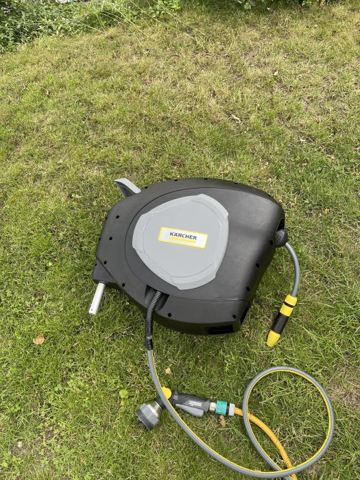 Karcher vattenspridare på gräs med anslutna slangar och kopplingar.