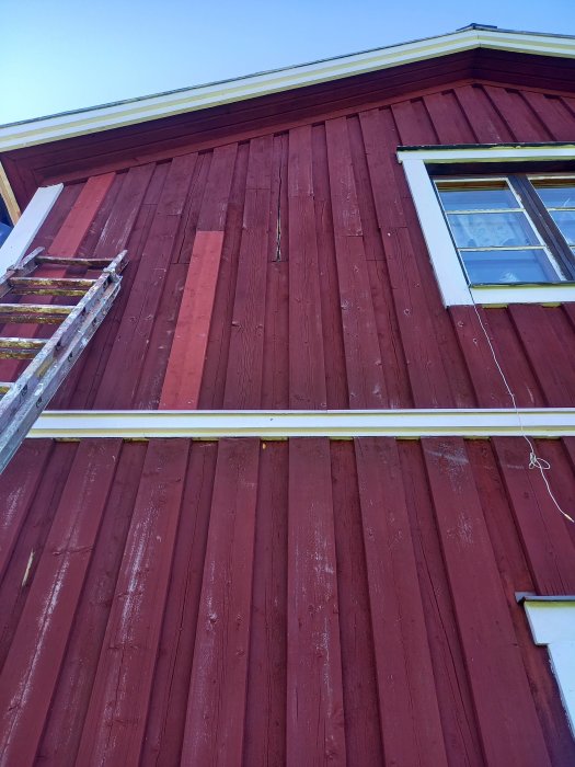 Rödmålat trähus med slitage och sprickor på fasaden som kan behöva täckas med latex.