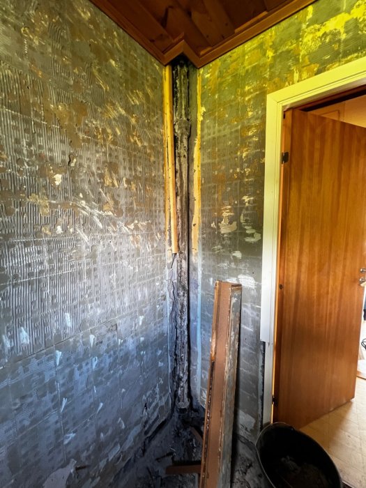 Renoverat badrum under bilning med exponerat avloppsrör och avlägsnad ytbeklädnad på väggar och golv.