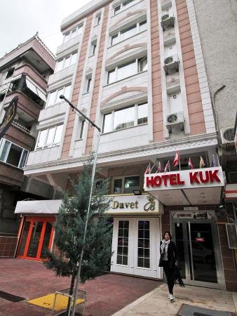 En leende kvinna som lämnar Hotel Kuk med en småstadens byggnader i bakgrunden.