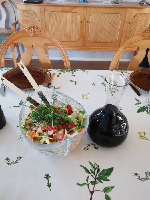 Färgglad Cajsa Warg-sallad med tärnade grönsaker och frukter serveras i en genomskinlig skål på dukat bord.