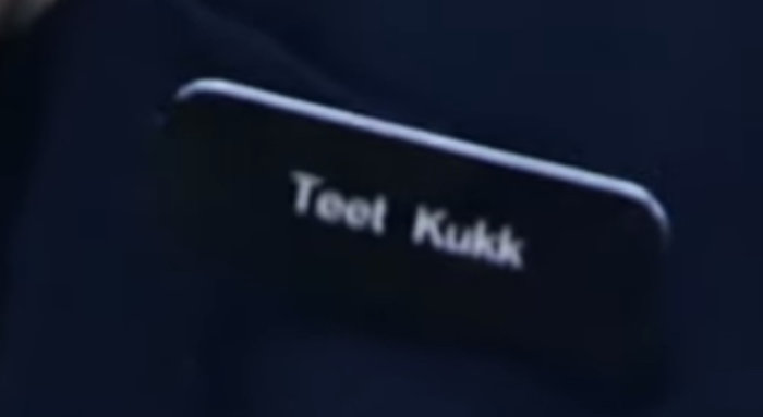 Närbild på texten "Teet Kukk" på ett objekt med otydlig kontext.