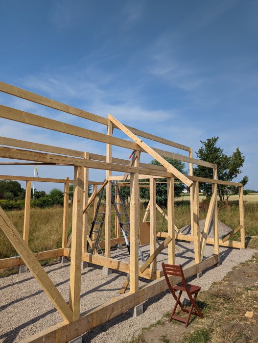 Trästomme i uppbyggnad för hus med synlig person som mäter träbjälke.