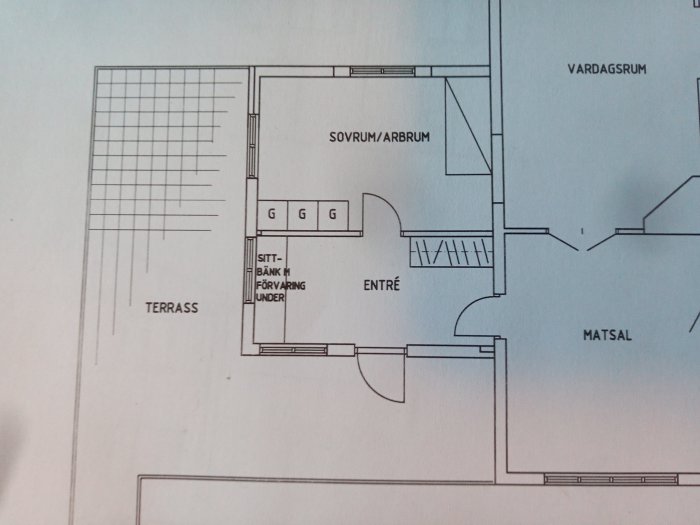 Ritning av ett hus med terrass, sovrum, entré och vardagsrum som visar symmetriska fönster och dörrplacering.