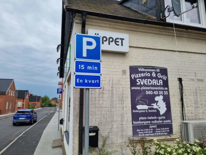 Parkeringskylt med 15 minuters begränsning och skylt för "Pizzeria & Grill SVEDALA" på en byggnad.