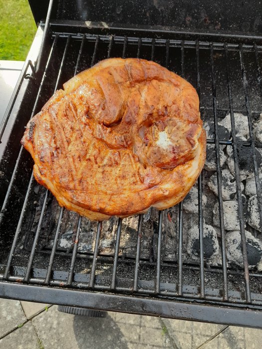 En stor flintastek som grillas på en kolgrill.