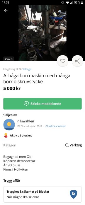 Gammal pelarborrmaskin i verkstadsmiljö med skruvstycke och verktyg i bakgrunden.