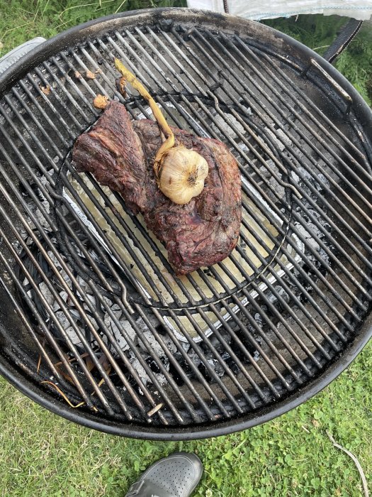 Högrev grillas på en kolgrill med en hel vitlök, användare berättar om tillagning enligt Niklas Ekstedts recept.