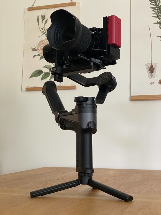 Professionell spegellös kamera monterad på en gimbal stabilisator står på ett bord.
