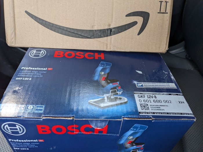 Bosch Professional trådlös kantfräs i förpackning med Amazon Prime-låda ovanpå, i ett fordon.