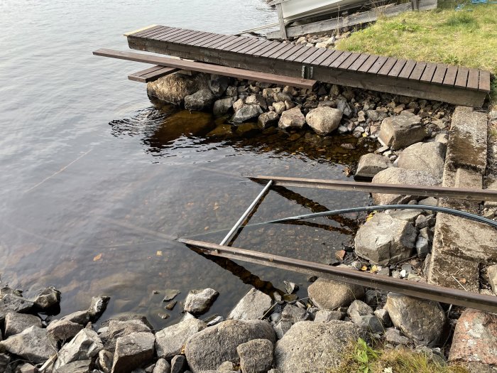 Reparerad metallstruktur för båtslip vid sjökant intill brygga.