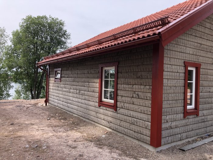 Nyrenoverat hus med målade vindskivor, färdigställda fönstersalningar och rödmålade fönsterfoder.