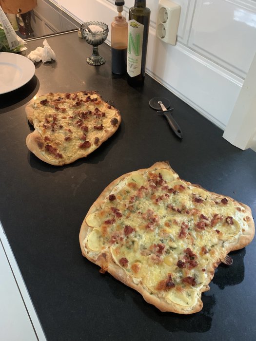 Två hemgjorda bianco pizzor med salsiccia och salvia på en köksbänk.