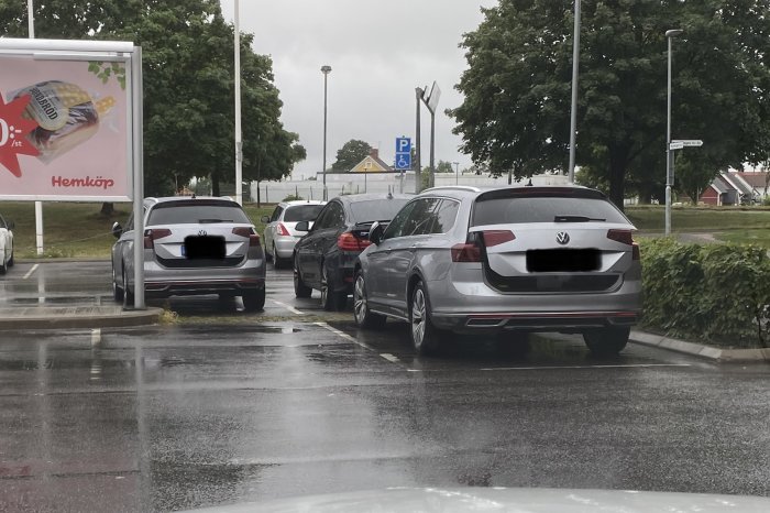 Tre bilar av samma märke parkerade i en rad på en regnig parkeringsplats.