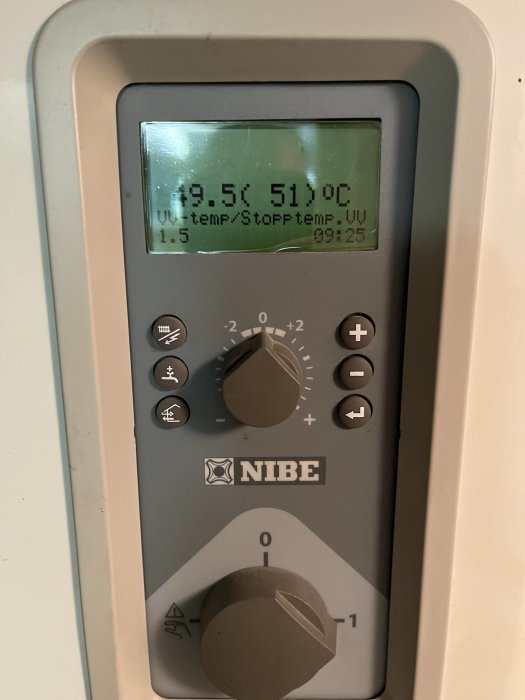 Närbild av en NIBE värmepumps kontrollpanel med display som visar temperaturinställningar.