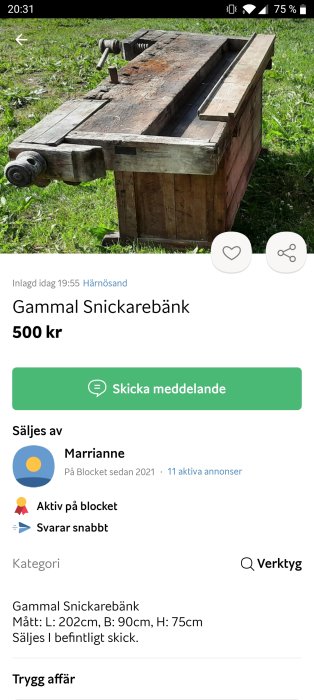 Gammal träsnickarbänk med skruvstycke utomhus på gräsmatta, använd och rustik.