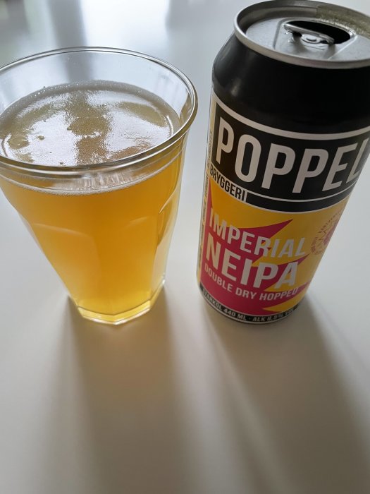 Ett glas fyllig öl bredvid en burk öl med etiketten "POPPEL IMPERIAL NEIPA DOUBLE DRY HOPPED".