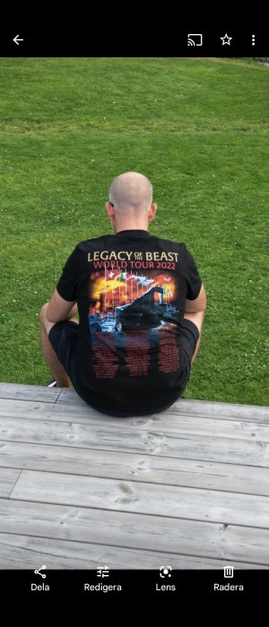 Person sett bakifrån som sitter på en trätrall med en t-shirt för en konsertturné.