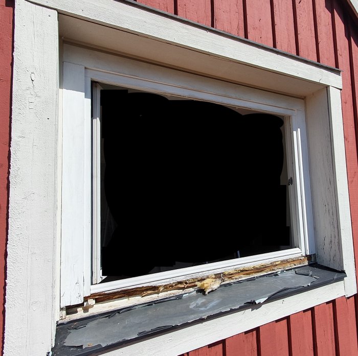 Skadat fönsterkarm i behov av renovering monterad på en rödmålad vägg.