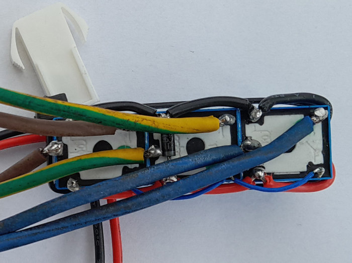 Öppen elektrisk kopplingsdosa med olika färgade ledningar och säkringar anslutna.