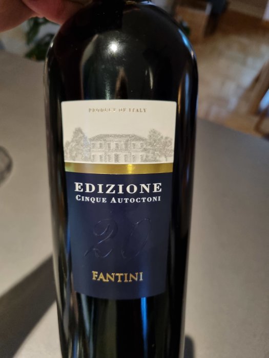 Flaska med italienskt vin, etikett: 'EDIZIONE Cinque Autoctoni FANTINI' mot suddig bakgrund.